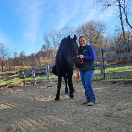 Dr. Amity Wise stands next to a black horse.
