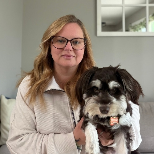 Terri Brickles holds a small, fluffy brown and white dog.